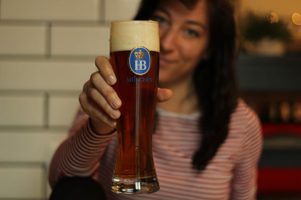 Woman holding beer from Munich Hofbräuerei into the camera