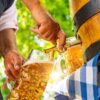 Ein Mann in Tracht zapft Bier aus einem Holzfaß in einen Maßkrug