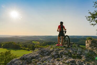 young woman admiring the awesome view over Frankonian Switzerland, during a mountain bike trip during golden hour in the evening