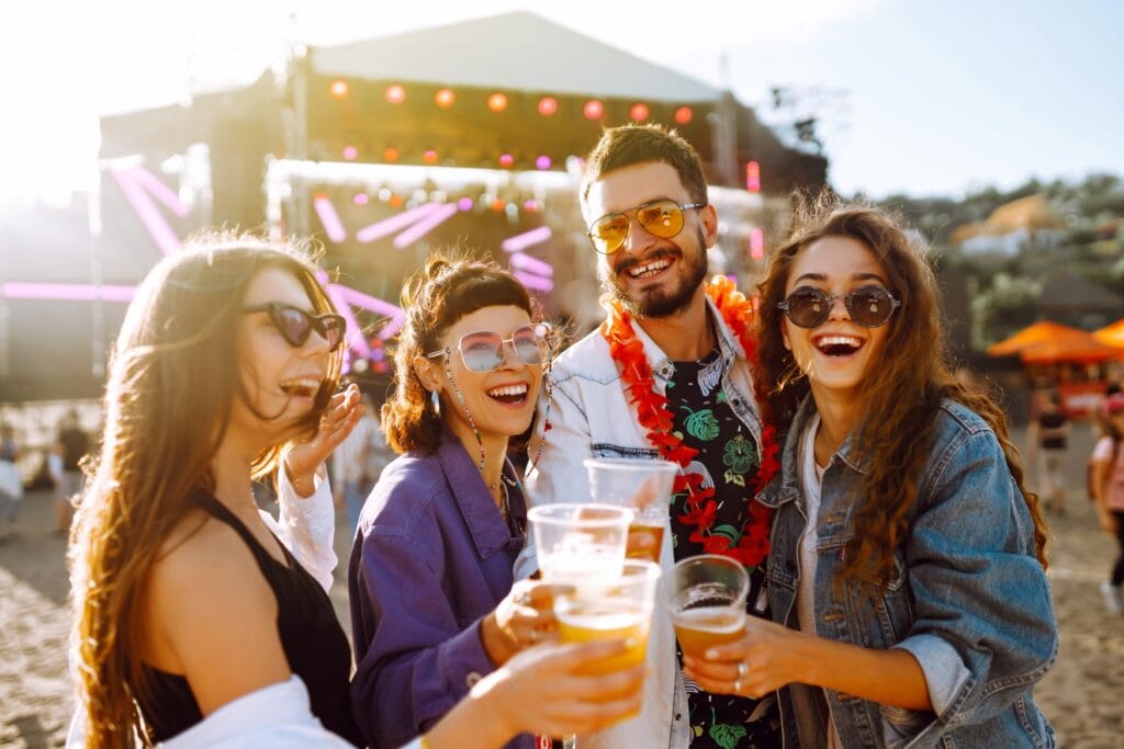 Vier junge Menschen stoßen auf einem Festival mit ihren Bierbechern an