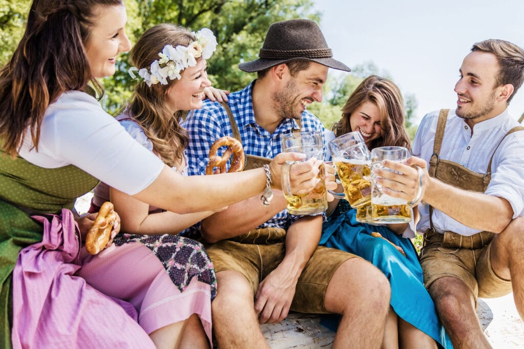 Fünf Freunde in Dirndl und Lederhosen stoßen mit bayerischem Bier an