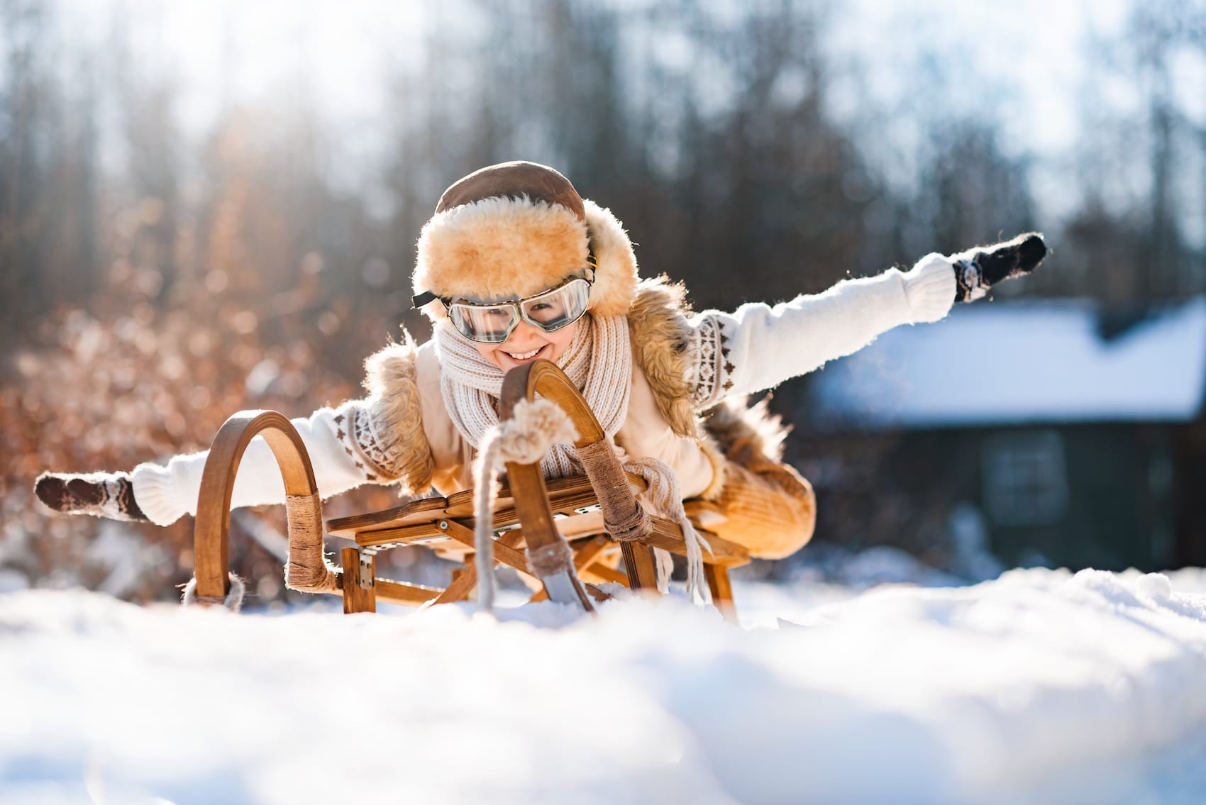 Lustiges kleines Kind fährt auf Schlitten im Schnee. Aktive Sportspiele in der Winterzeit.