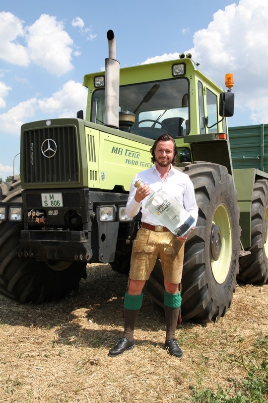 Johannes Schlemmer with a gigantic bottle of Bavarian Spirits in front of a tractor