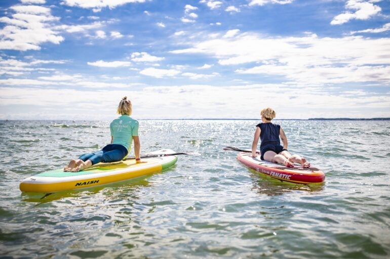 Zwei Frauen machen Yoga auf SUP an der Ostsee