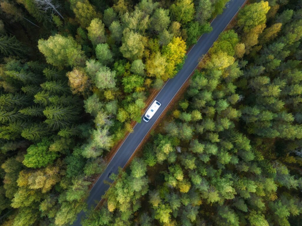 Aerial view of a camping bus driving through the woods