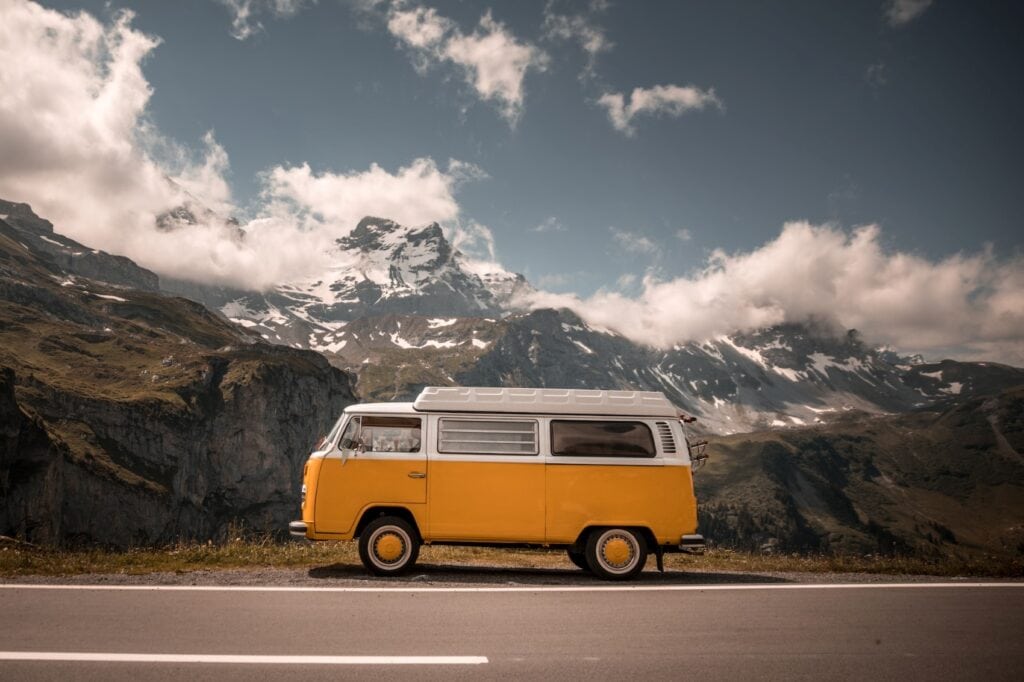 Yellow camping bus in front of a mountain range