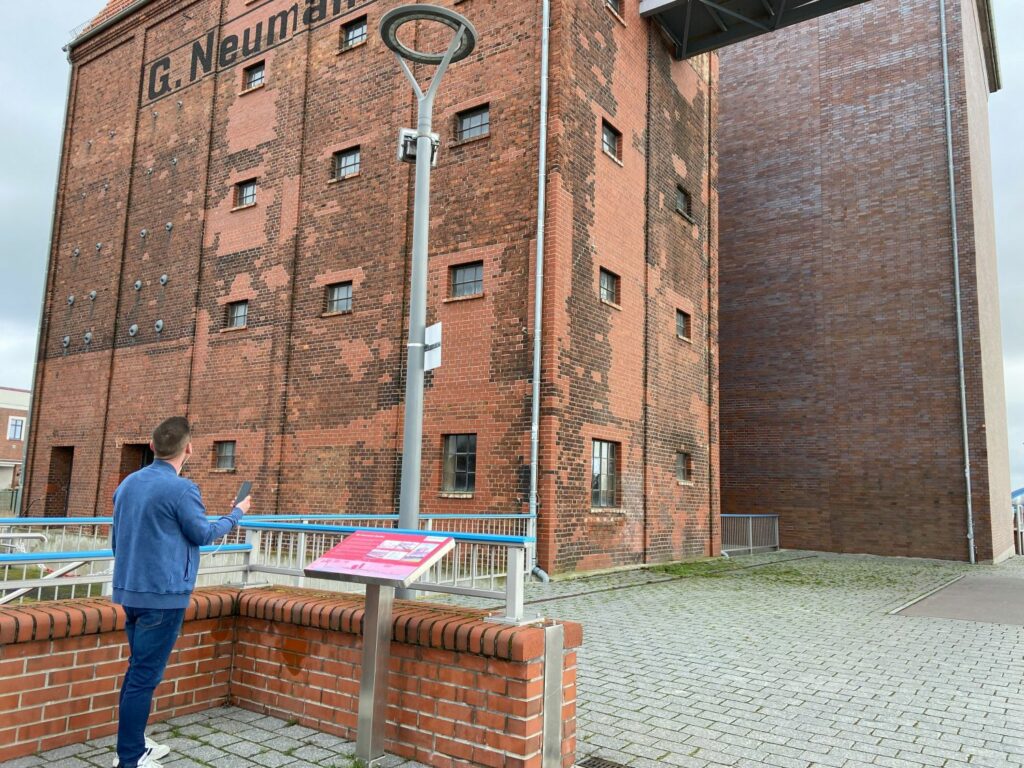 Woman using an audio guide in front of an old industry building