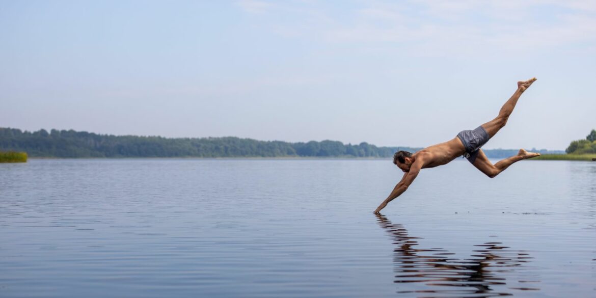 Ein Mann macht einen Kopfsprung in einen See im Herzogtum Lauenburg