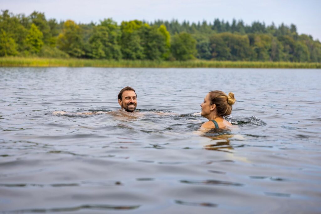 A man and a woman bathing in a lake in the forest
