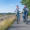 Zwei Personen fahren mit dem Rad am einem Seerundweg im Lausitzer Seenland entlang