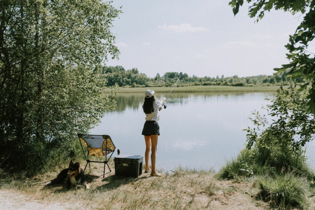 Eine Frau steht an einem See und angelt