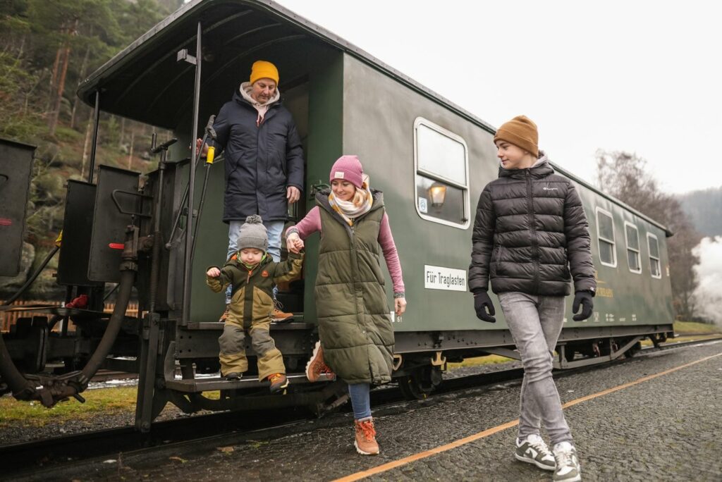 Family in front of a historic railway car in the Zittau mountains