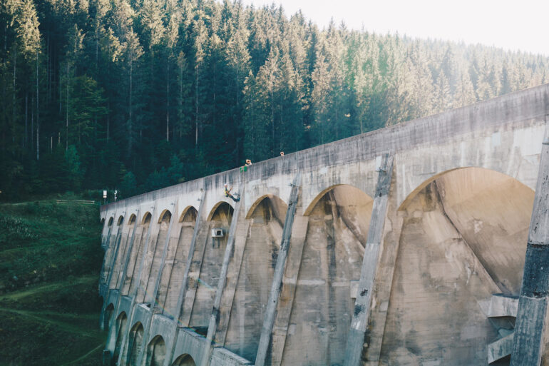 A man climbing down the Linach Dam with a rope in the black forest