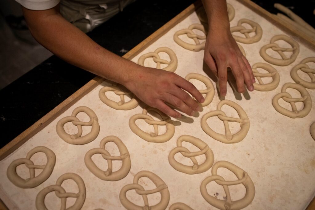 One person places pretzels on a baking tray