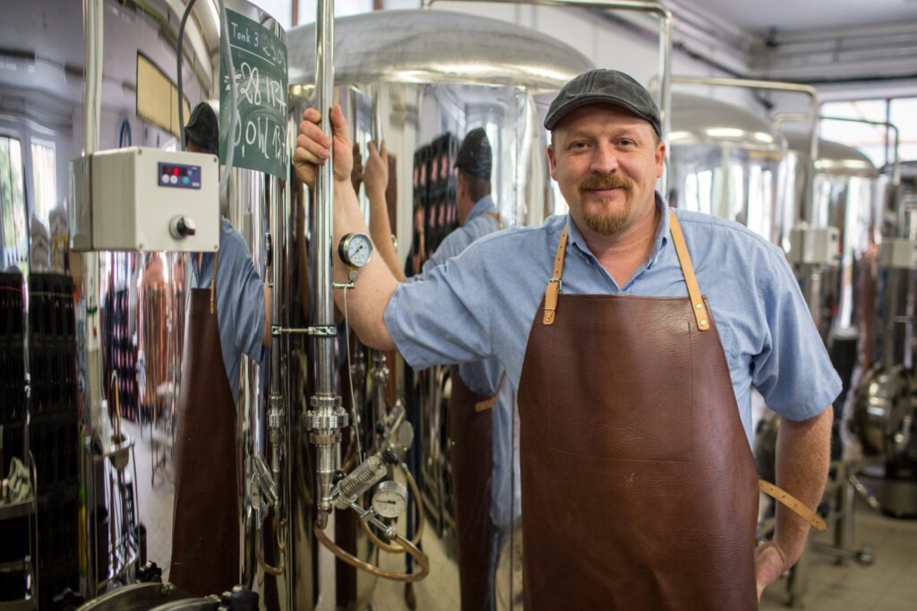 A brewer stands in front of a brewing plant