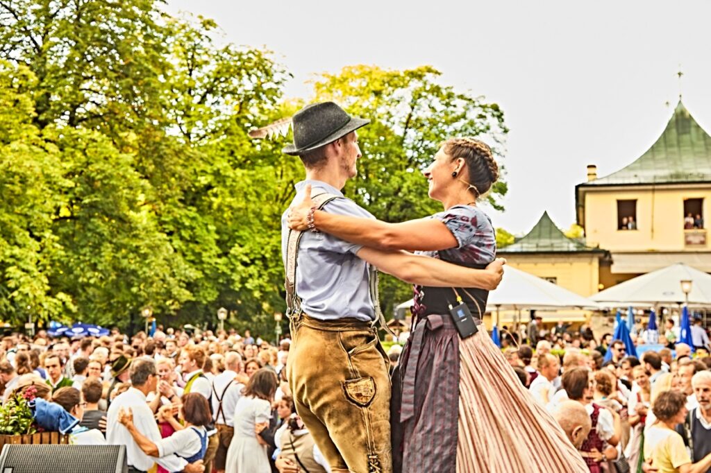 A man and a woman, both in traditional costume, dance at a Munich folk festival