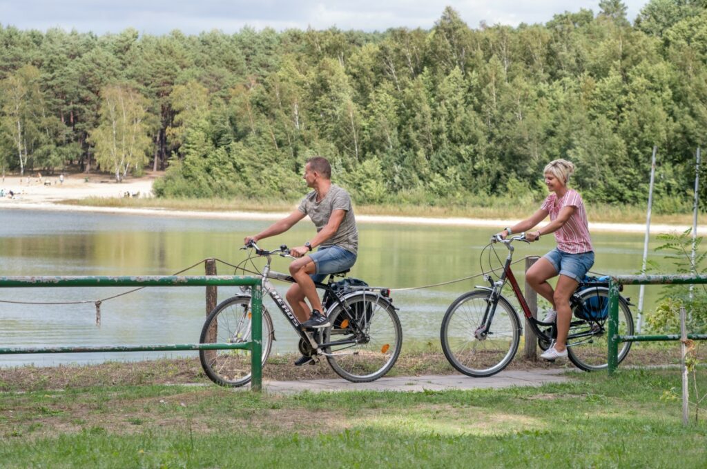 Two people cycle along the shore of Lake Deulowitz in the Lusatian Lakeland.