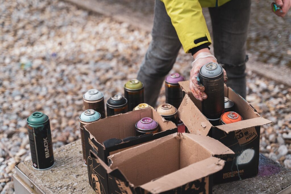 A person takes out a spray paint can from a cardboard box