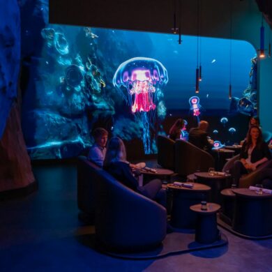 Guests eat in front of an underwater backdrop projected onto the wall in the "eatrenalin" gastronomy experience at Europa-Park in Baden-Württemberg