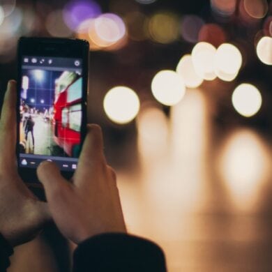 Person fotografiert Straßenverkehr bei Nacht mit dem Handy