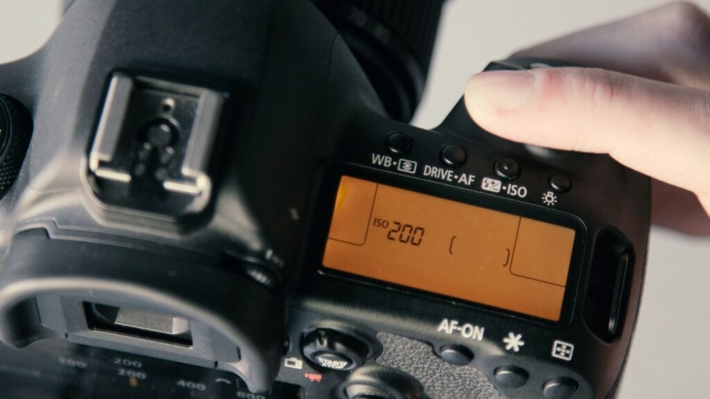 Eine Person stellt den ISO-Wert an einer Digitalkamera ein