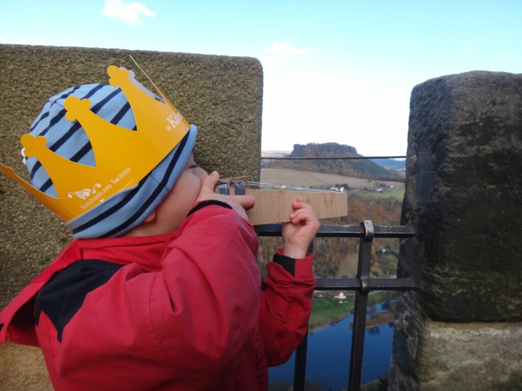 A child aims a toy crossbow from the battlements of a castle