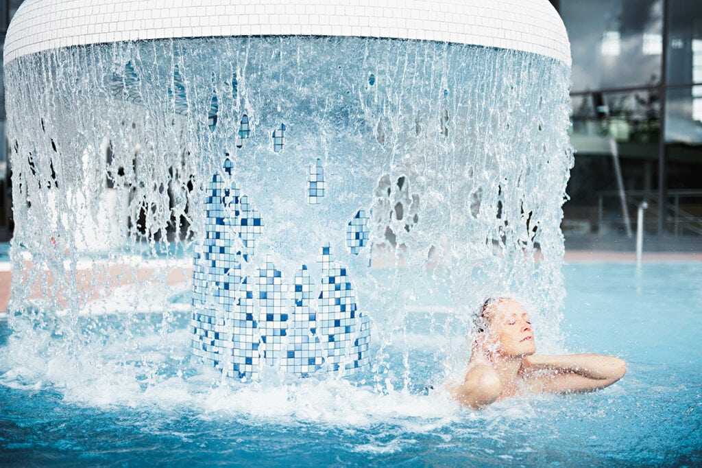 Eine Frau badet in einem Schwimmbad mit Wasserfontäne