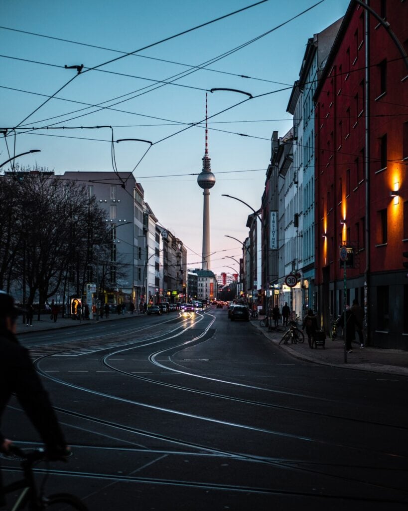 Am Ende einer Straße ist der Berliner Fernsehturm bei Sonnenaufgang zu sehen.