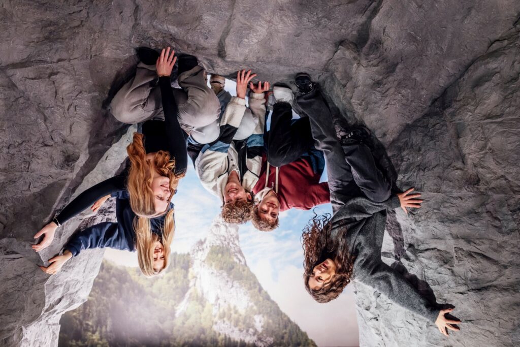 In a picture illusion, it looks as if a group of young people are sitting upside down on a rock face.