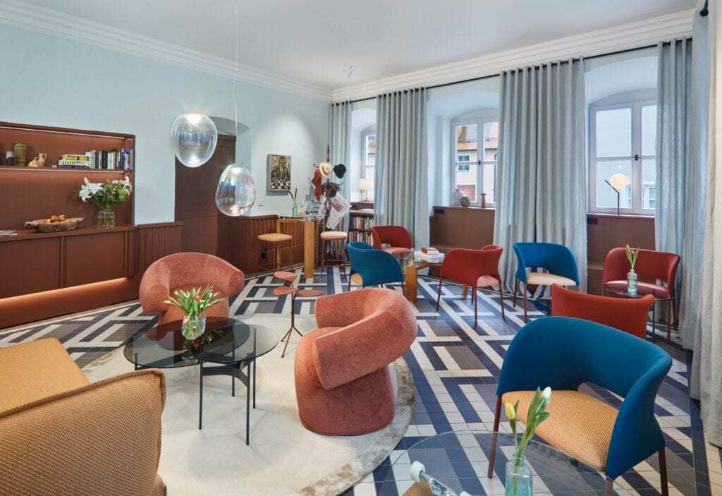 Der Salon im Hotel Engelwirt, ein Raum mit hohen Fenstern und vielen modernen, gepolsterten Sesseln