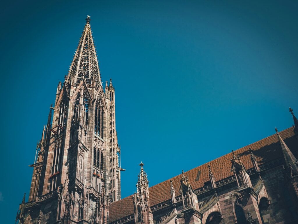 Blick auf den Turm des Freiburger Münster, der in den blauen Himmel ragt