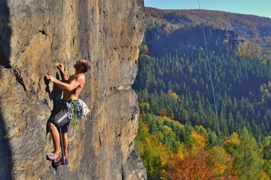 Ein Mann klettert im Vorstieg an einer Felswand in der Sächsischen Schweiz.