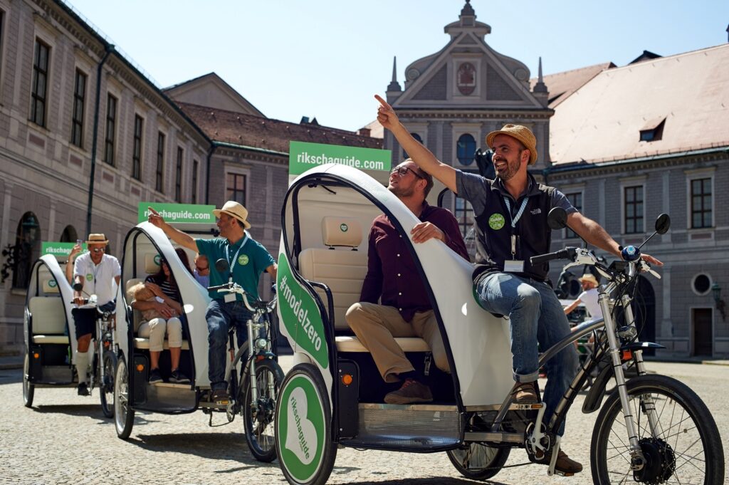 A group of tourists ride through Munich in rickshaws. A sustainable way to experience the city.