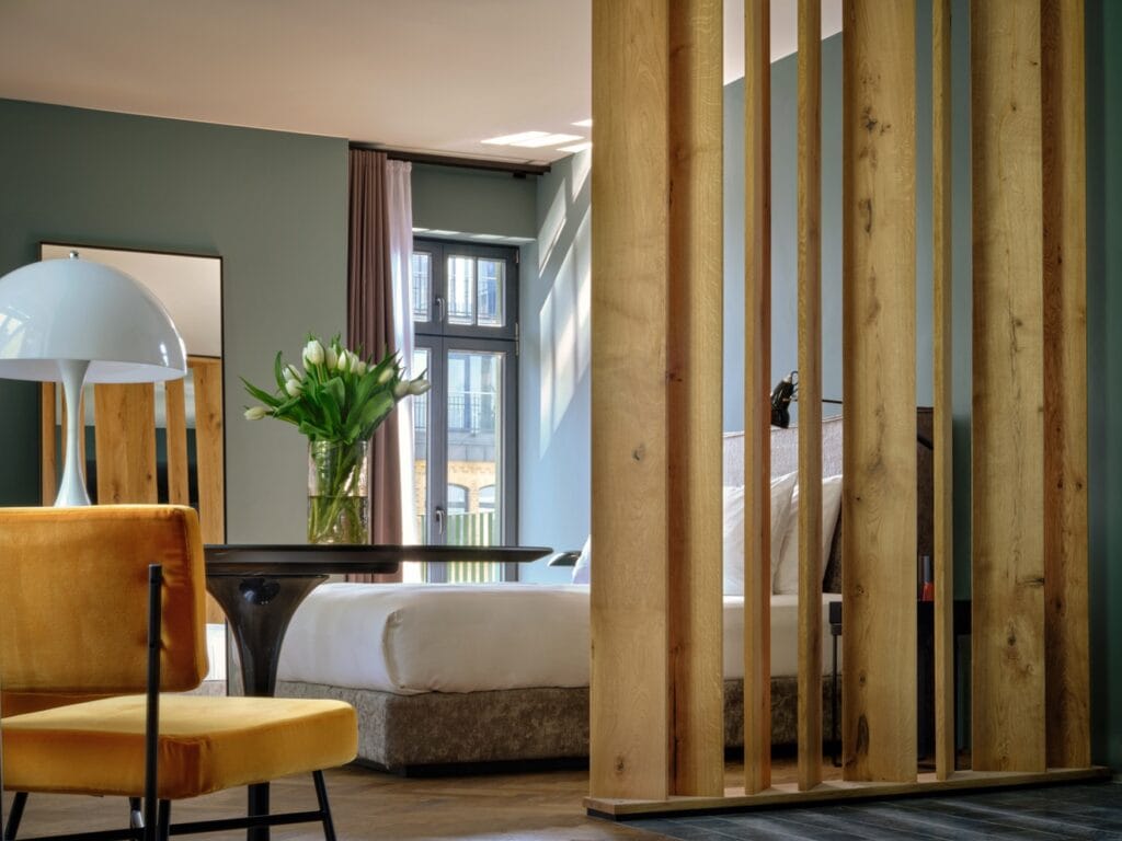 Blick in ein Zimmer im Sly Berlin, mit Sitzgelegenheit im Vorder- und Bett im Hintergrund