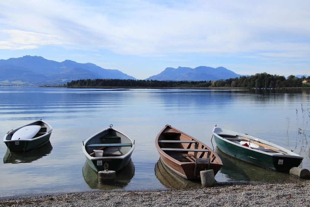 Vier Boote liegen am Ufer eines Bergsees