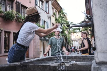 Menschen erfrischen sich an einem Brunnen in Freiburg