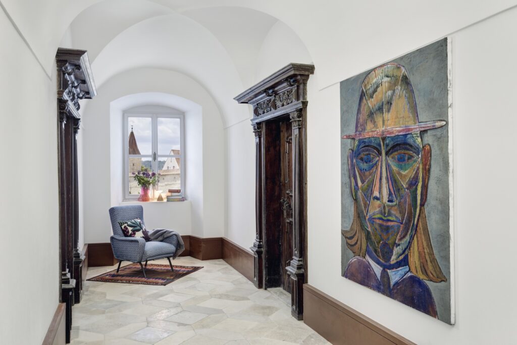 Hallway with artwork and armchair at the Hotel Engelwirt in Berching