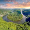 Blick auf eine Flussschleife in U-Form von einem hohen Aussichtspunkt. Die durch die Schleife gebildete Halbinsel ist ebenso bewaldet wie das gesamte Umland. Das Wasser ist spiegelglatt.