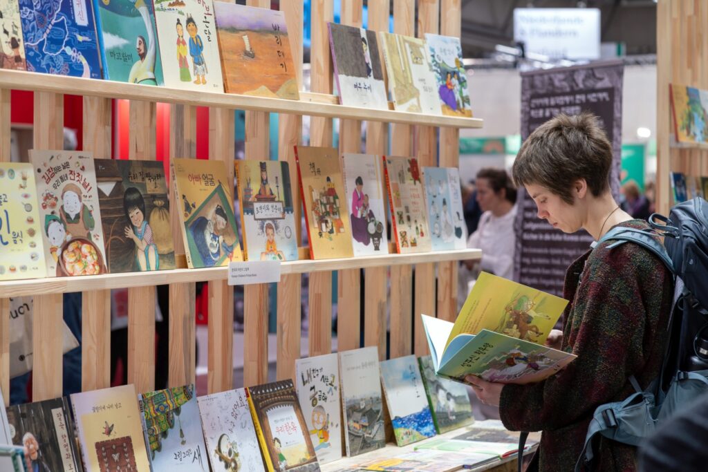 A visitor to the Leipzig Book Fair leafs through a Korean children's book in front of a shelf