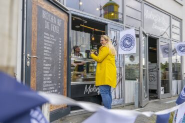 Eine Frau im Friesennerz bestellt bei Mehrfisch in Eckernfoerde ein veganes Fischbrötchen