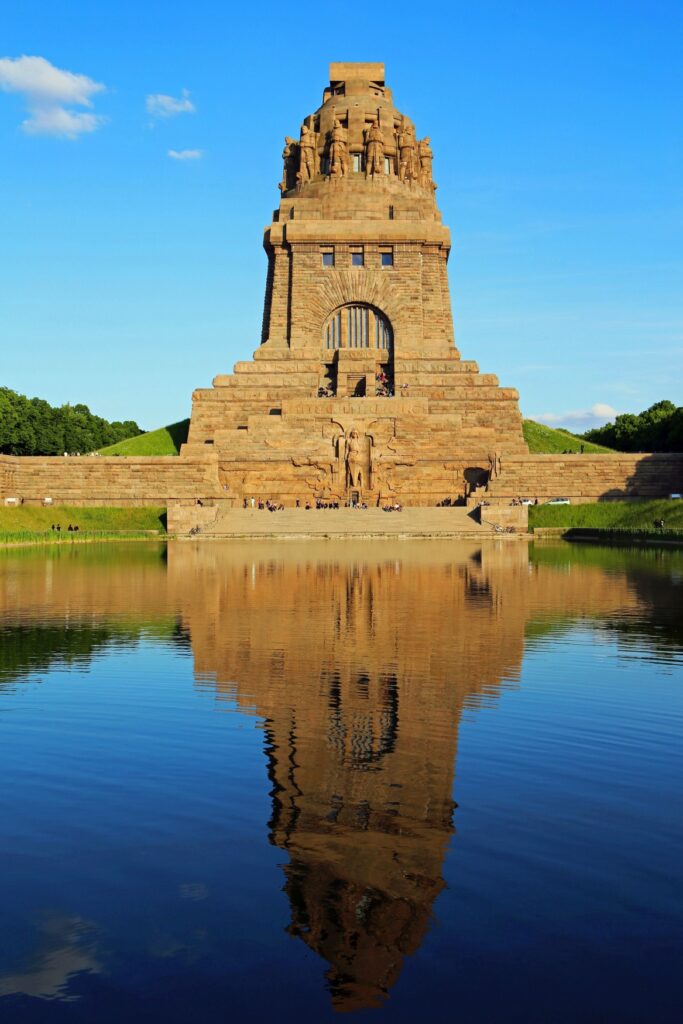 The Monument to the Battle of the Nations with the water basin in front of it, blue sky behind it