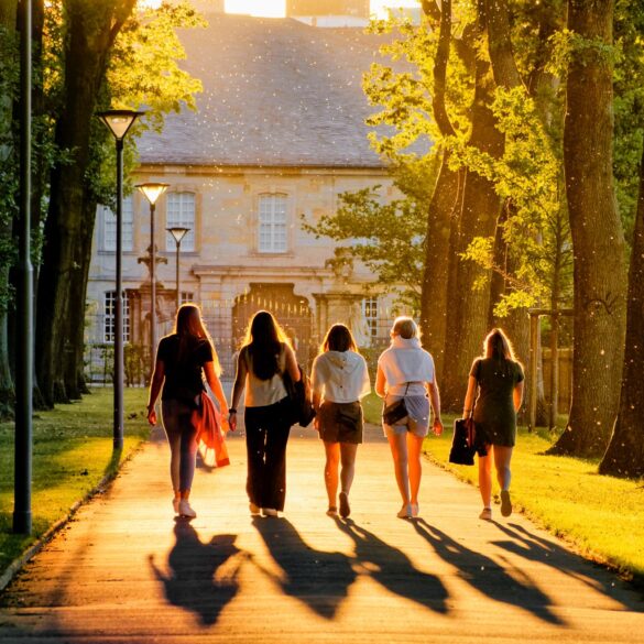 Fünf Frauen laufen im Sonnenschein durch einen Park
