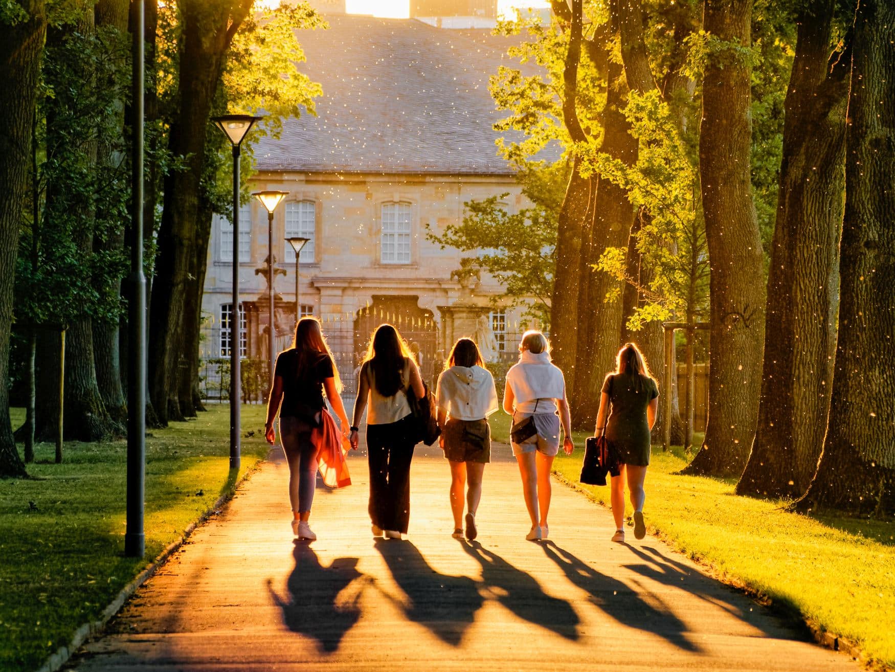 Fünf Frauen laufen im Sonnenschein durch einen Park