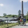 Two cyclists pushing their bikes in front of an industrial heritage site in Berlin