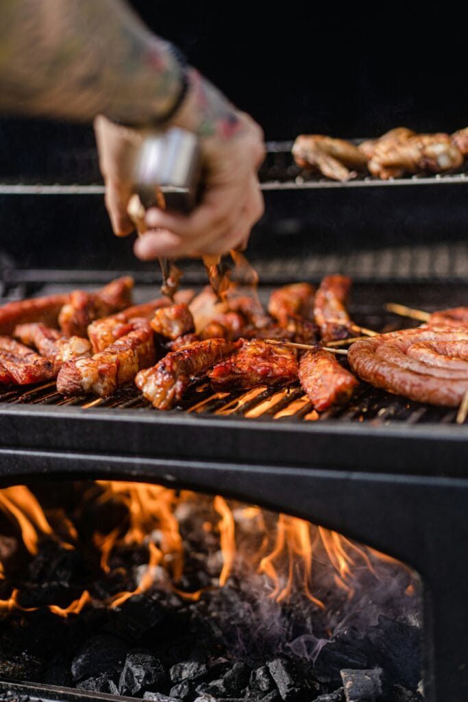 Ein Mann wendet Fleisch auf einem Grill