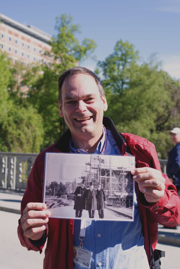 Hartmut Speck hält ein historisches Foto auf der Brücke zur Museumsinsel ins Bild.