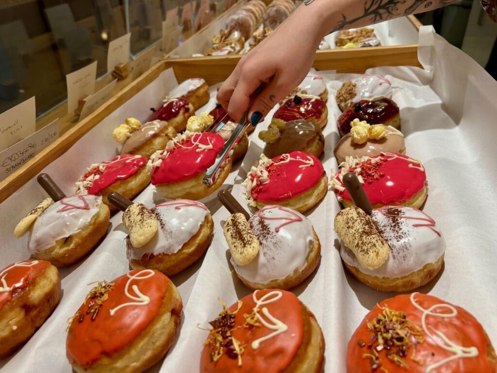 Pfannkuchen in der Auslage. Ein Pfeil auf der Glasur weist auf die ideale Stelle zum Hineinbeissen hin