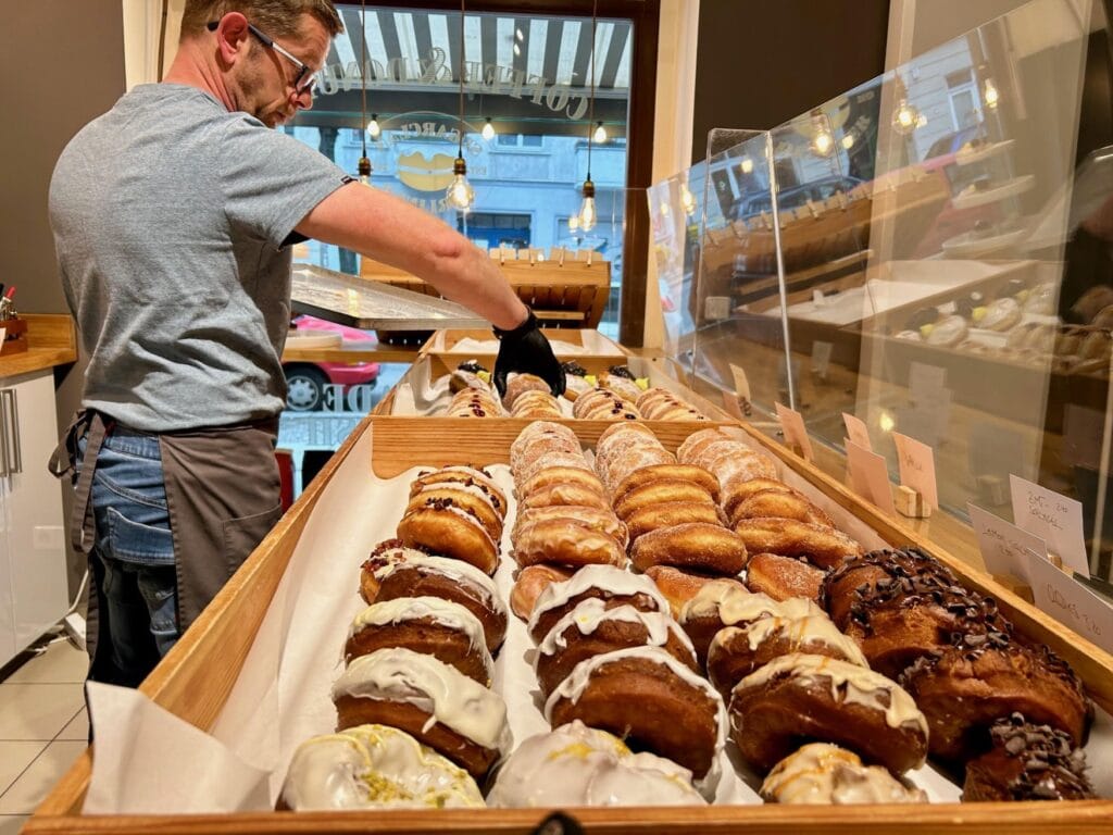 Ein Mitarbeiter legt die fertigen Krapfen in die Auslage