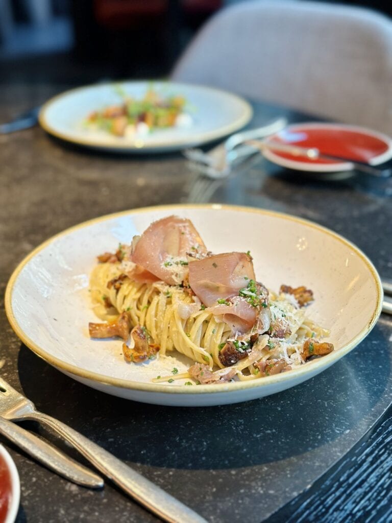 Auf einem Teller liegt ein Gericht mit Pfifferlingen, Spaghetti und Schweinefilet 