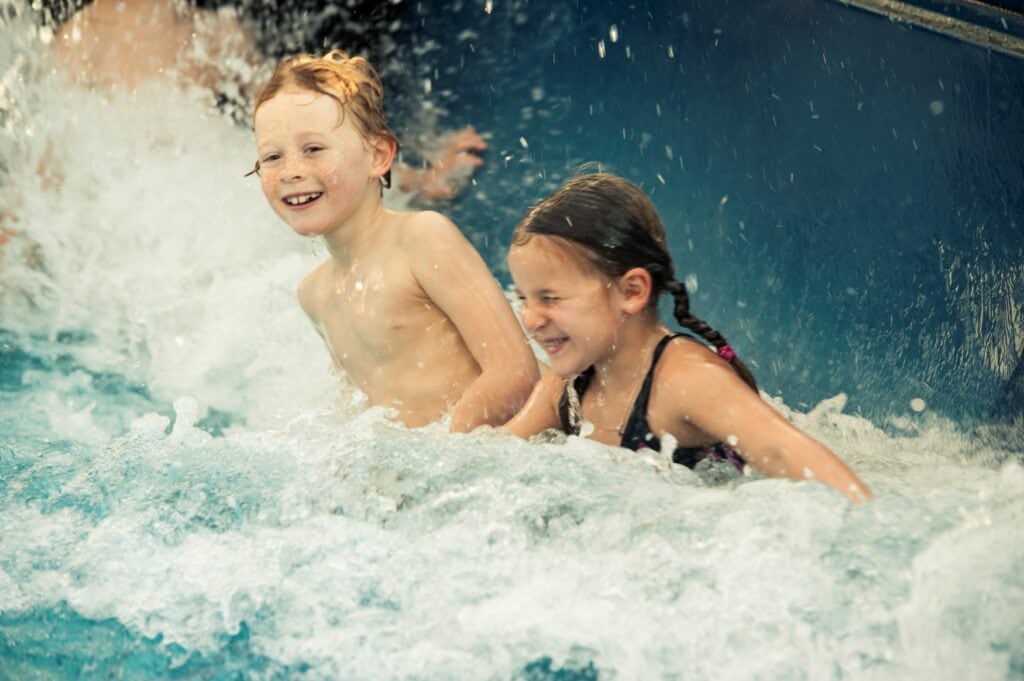 Zwei Kinder schwimmen in einem Wellenbad